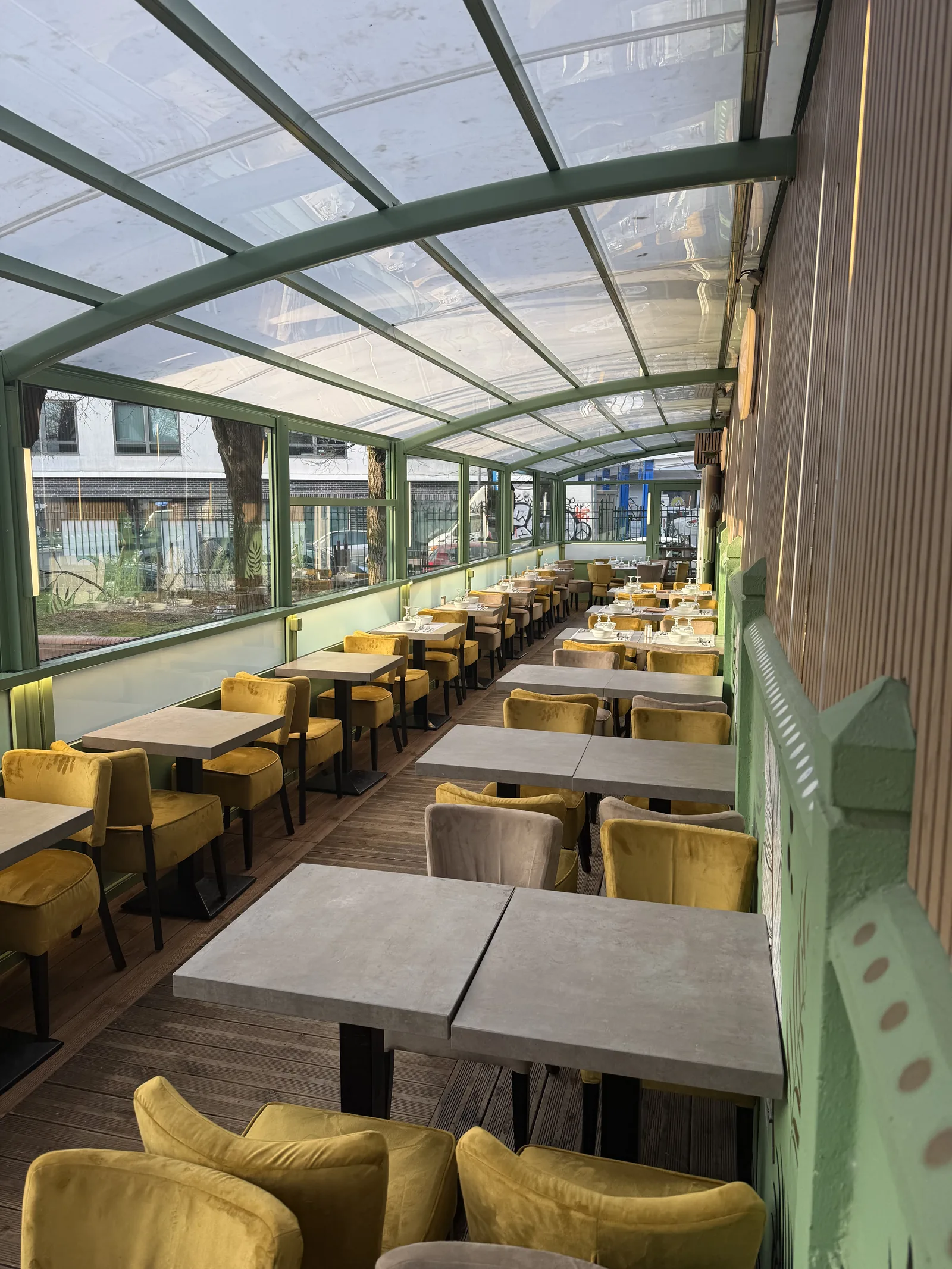 Terrasse bioclimatique de La Table Fleurie, pergola vitrée et fauteuils moutarde